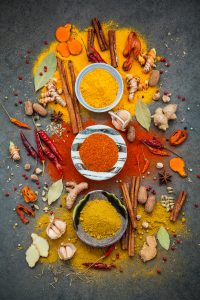 Various of spices and herbs in ceramic bowl. Flat lay of spices ingredients chilli ,pepper corn, garlic, thyme, oregano, cinnamon, star anise, nutmeg, mace, ginger and bay leaves on dark stone background.