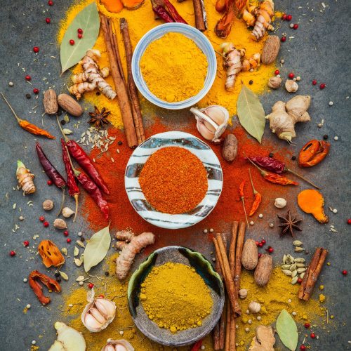 Various of spices and herbs in ceramic bowl. Flat lay of spices ingredients chilli ,pepper corn, garlic, thyme, oregano, cinnamon, star anise, nutmeg, mace, ginger and bay leaves on dark stone background.